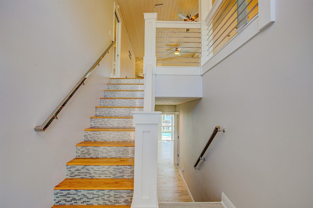 staircase with ceiling fan, hardwood / wood-style floors, and a towering ceiling