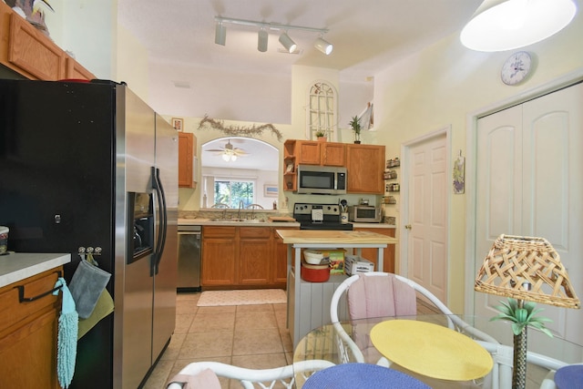1711 Old Beach Rd, Saint Augustine, FL 32080 - kitchen with stainless steel appliances, light countertops, light tile patterned flooring, rail lighting, and brown cabinetry