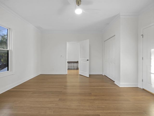 empty room with ornamental molding, ceiling fan, baseboards, and wood finished floors