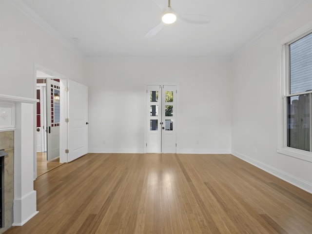 unfurnished living room featuring ceiling fan, crown molding, a fireplace, and light wood-style floors