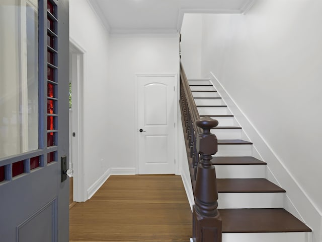 stairway featuring ornamental molding, baseboards, and wood finished floors