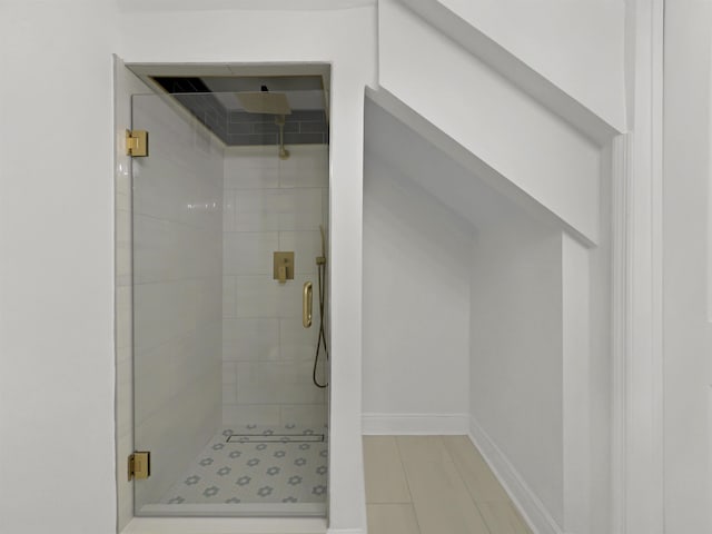 full bathroom featuring a shower stall and baseboards