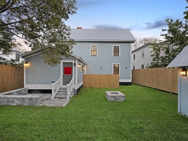 back of property featuring entry steps, a lawn, an outbuilding, and a fenced backyard