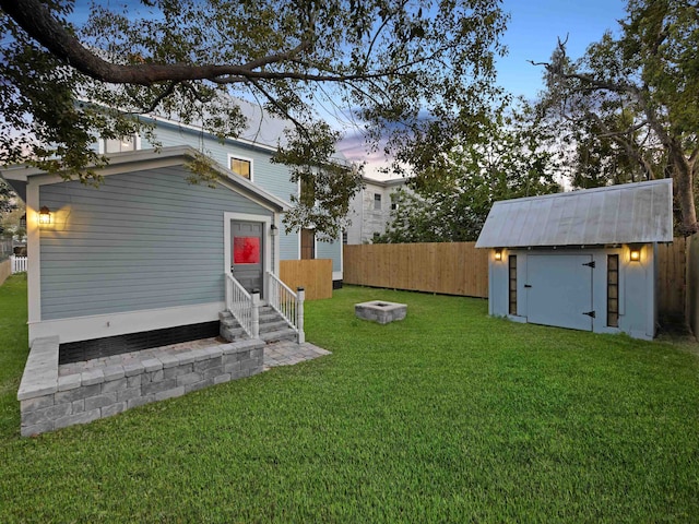 view of yard with an outbuilding, entry steps, fence, a shed, and a fire pit