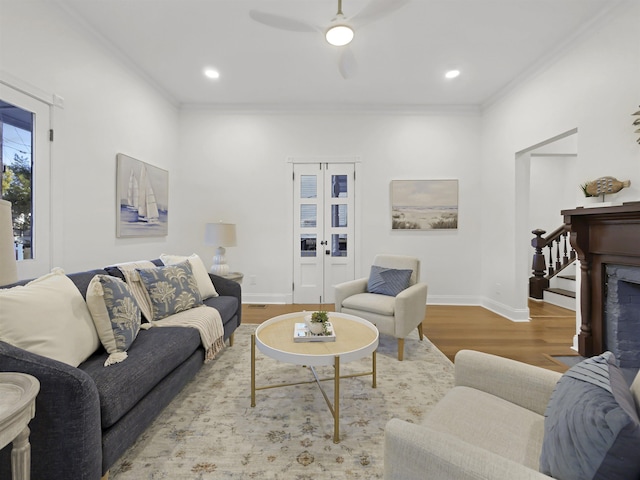 living room with a fireplace, wood finished floors, baseboards, french doors, and ornamental molding