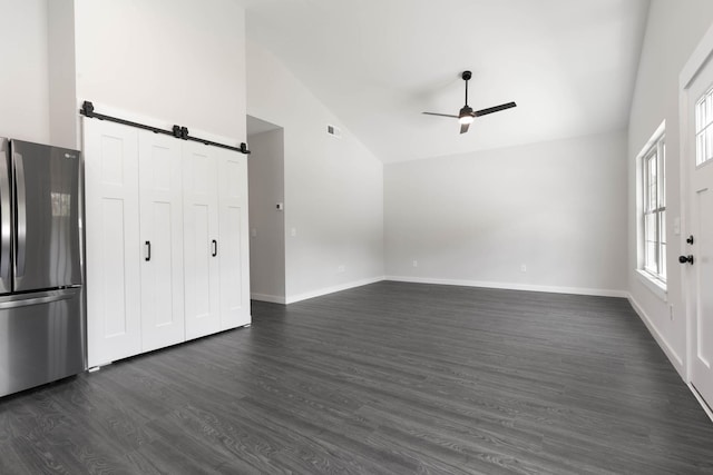 unfurnished living room with vaulted ceiling, a barn door, ceiling fan, dark wood-style floors, and baseboards