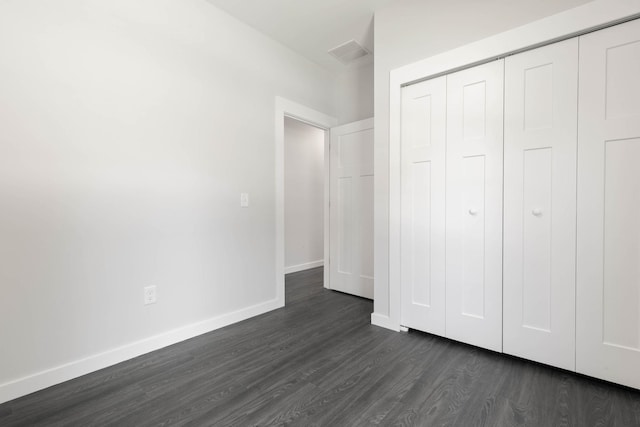 unfurnished bedroom featuring dark wood-style floors, baseboards, and a closet