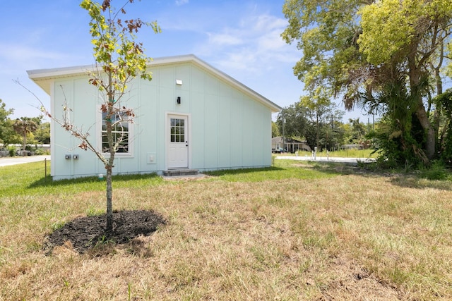 rear view of property featuring a yard and board and batten siding