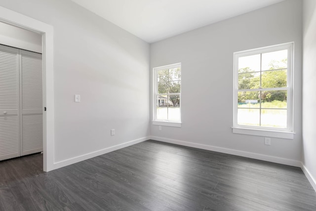 unfurnished bedroom featuring dark wood finished floors, baseboards, and a closet