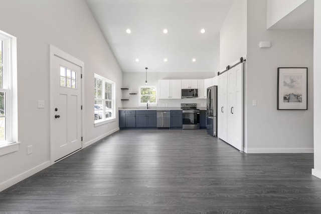 kitchen with stainless steel appliances, high vaulted ceiling, a sink, a barn door, and light countertops
