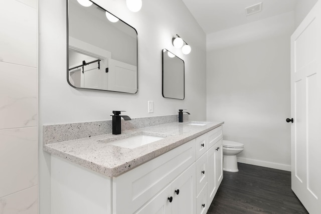 full bathroom featuring double vanity, toilet, baseboards, and wood finished floors