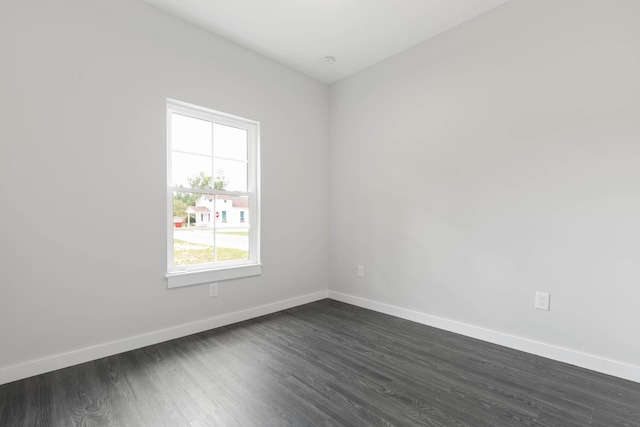 unfurnished room featuring baseboards and dark wood finished floors