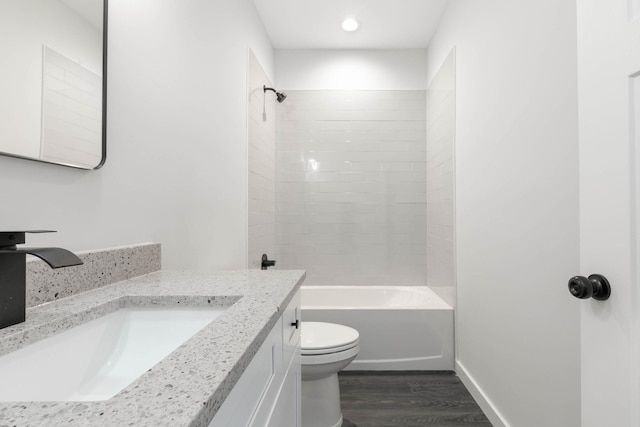 bathroom with wood finished floors, toilet,  shower combination, vanity, and baseboards