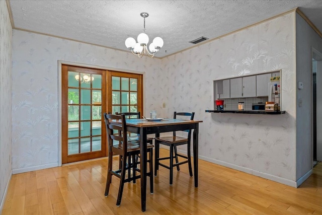 603 Mariposa St, Saint Augustine Beach, FL 32080 - dining room with a textured ceiling, a chandelier, light wood-style floors, crown molding, and wallpapered walls
