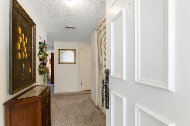 hallway featuring a textured ceiling and light carpet