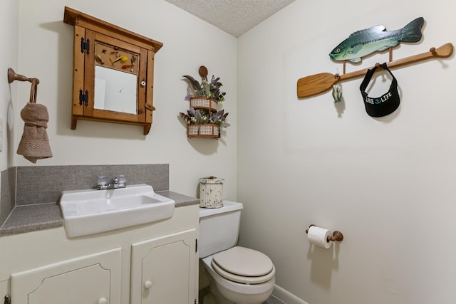 bathroom with vanity, toilet, and a textured ceiling