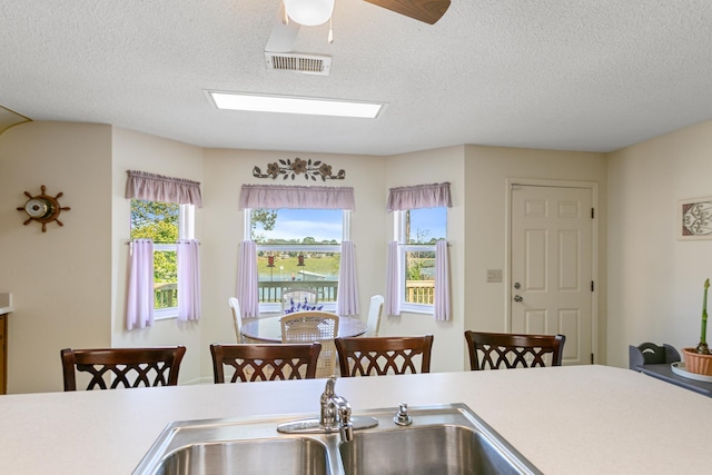 kitchen with a textured ceiling, a water view, and ceiling fan