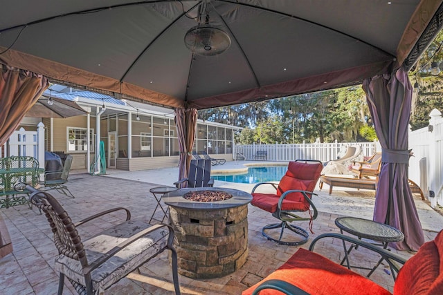 view of patio with a sunroom, a fire pit, and a fenced in pool