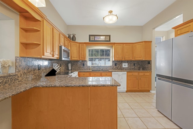 kitchen with kitchen peninsula, appliances with stainless steel finishes, decorative backsplash, sink, and light tile patterned floors