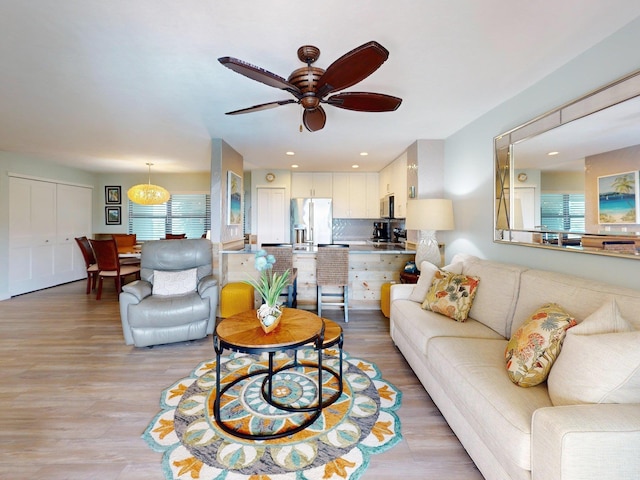 living room with ceiling fan and light hardwood / wood-style flooring