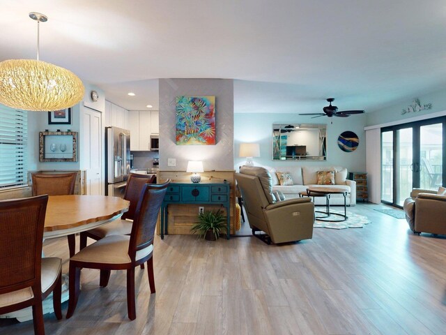 dining space featuring ceiling fan with notable chandelier and light hardwood / wood-style flooring