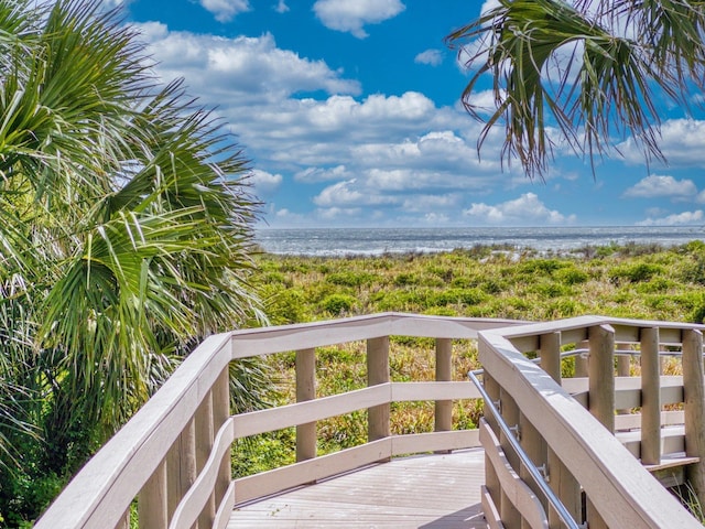 wooden deck featuring a water view and a beach view