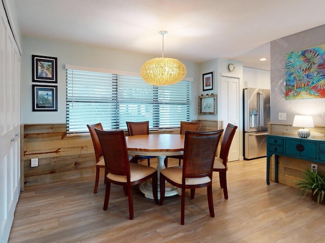 dining space featuring wooden walls, a chandelier, and light wood-type flooring