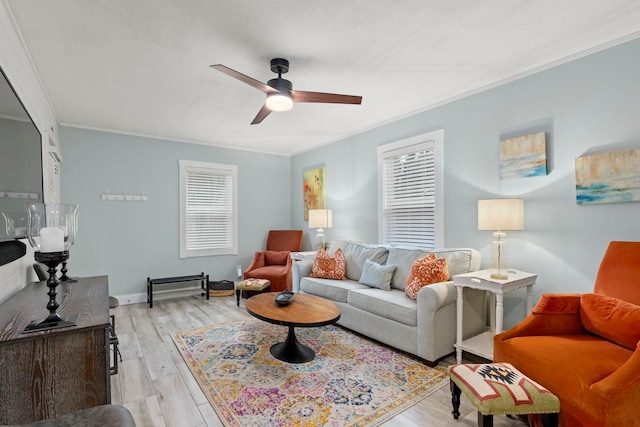 living area with crown molding, a healthy amount of sunlight, a ceiling fan, and light wood finished floors