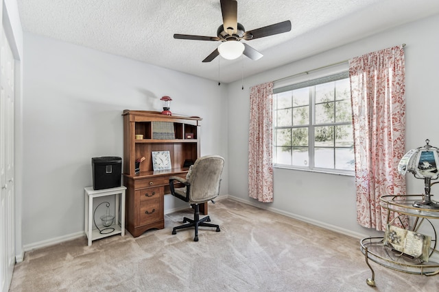 home office featuring light carpet, ceiling fan, baseboards, and a textured ceiling