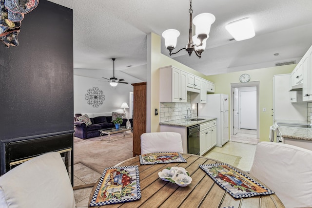 dining area with lofted ceiling, a textured ceiling, light carpet, ceiling fan with notable chandelier, and visible vents