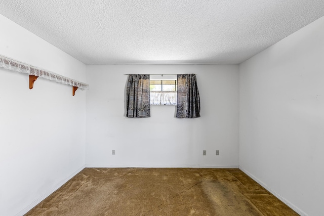carpeted spare room with baseboards and a textured ceiling