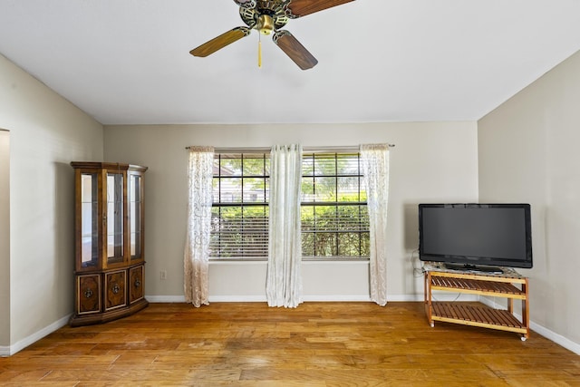 living area with baseboards, wood finished floors, and ceiling fan