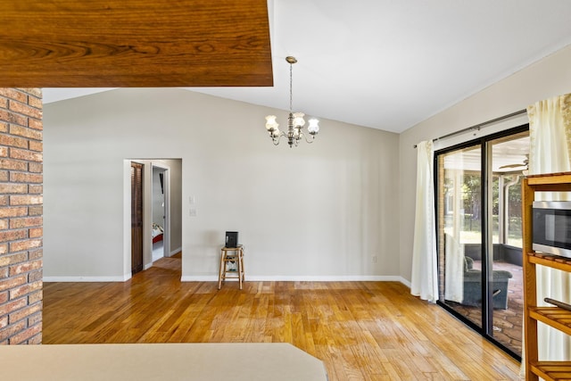 unfurnished room featuring vaulted ceiling, a chandelier, hardwood / wood-style floors, and baseboards