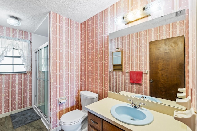 bathroom featuring a shower stall, toilet, wood finished floors, and wallpapered walls