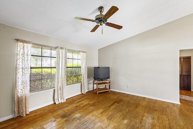 unfurnished living room with hardwood / wood-style flooring, baseboards, vaulted ceiling, and a ceiling fan