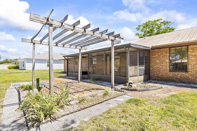 back of property with a pergola, a sunroom, brick siding, and a lawn