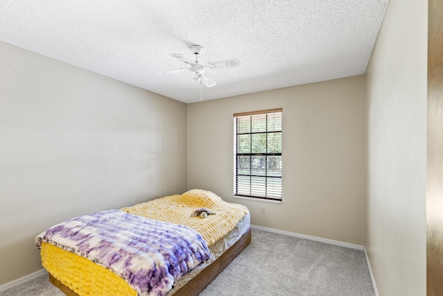 carpeted bedroom featuring a textured ceiling, a ceiling fan, and baseboards