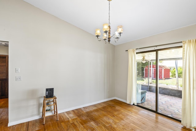 spare room featuring wood-type flooring, baseboards, lofted ceiling, and a chandelier