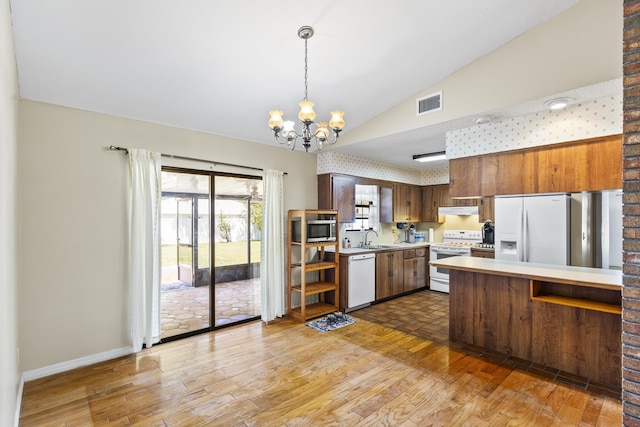 kitchen with under cabinet range hood, an inviting chandelier, light countertops, visible vents, and white appliances