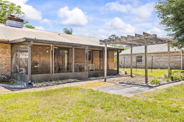 rear view of property featuring a pergola, fence, a yard, brick siding, and a sunroom