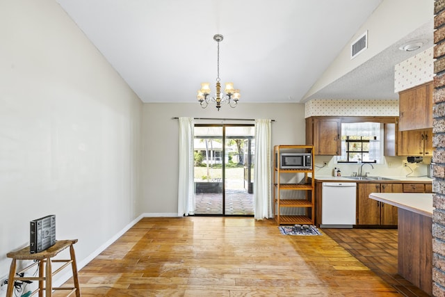kitchen with a sink, stainless steel microwave, visible vents, dishwasher, and light countertops