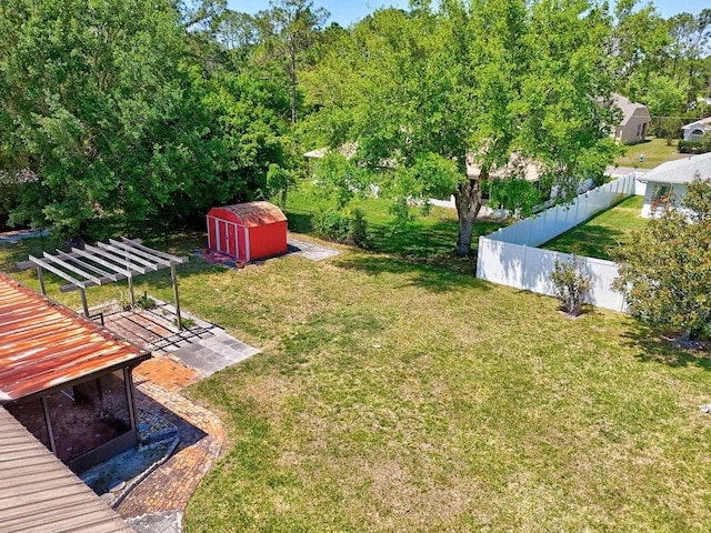 view of yard featuring fence, an outbuilding, a storage unit, and a pergola