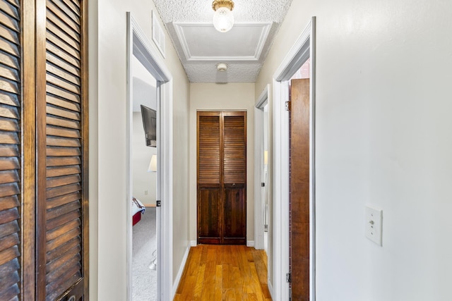 corridor featuring wood finished floors, a textured ceiling, and baseboards