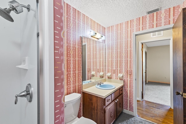 bathroom featuring vanity, toilet, wallpapered walls, and visible vents