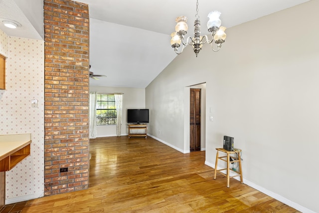 unfurnished dining area with vaulted ceiling, baseboards, wood finished floors, and ceiling fan with notable chandelier