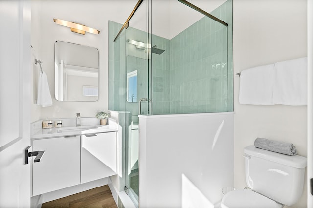 bathroom featuring wood-type flooring, vanity, toilet, and walk in shower