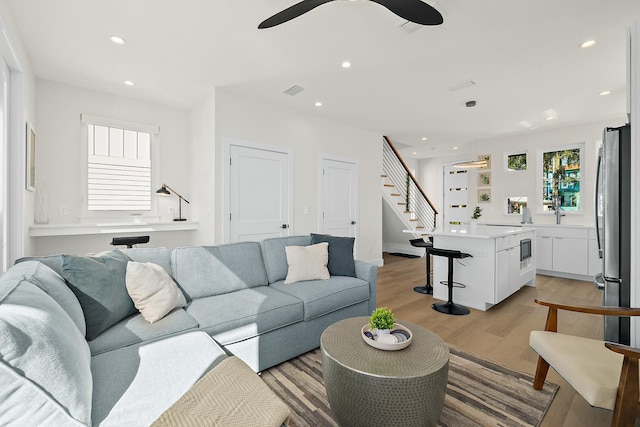 living room with light hardwood / wood-style flooring, ceiling fan, and sink