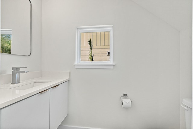 bathroom with vanity, toilet, and lofted ceiling