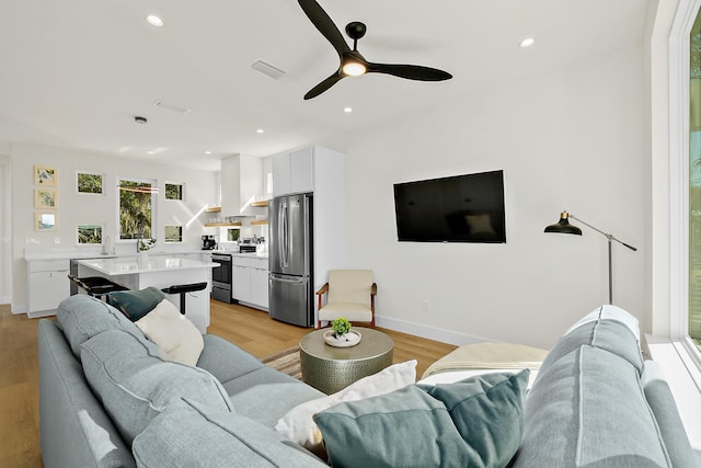 living room featuring ceiling fan and light hardwood / wood-style flooring