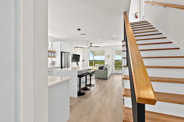 stairs featuring ceiling fan and hardwood / wood-style flooring